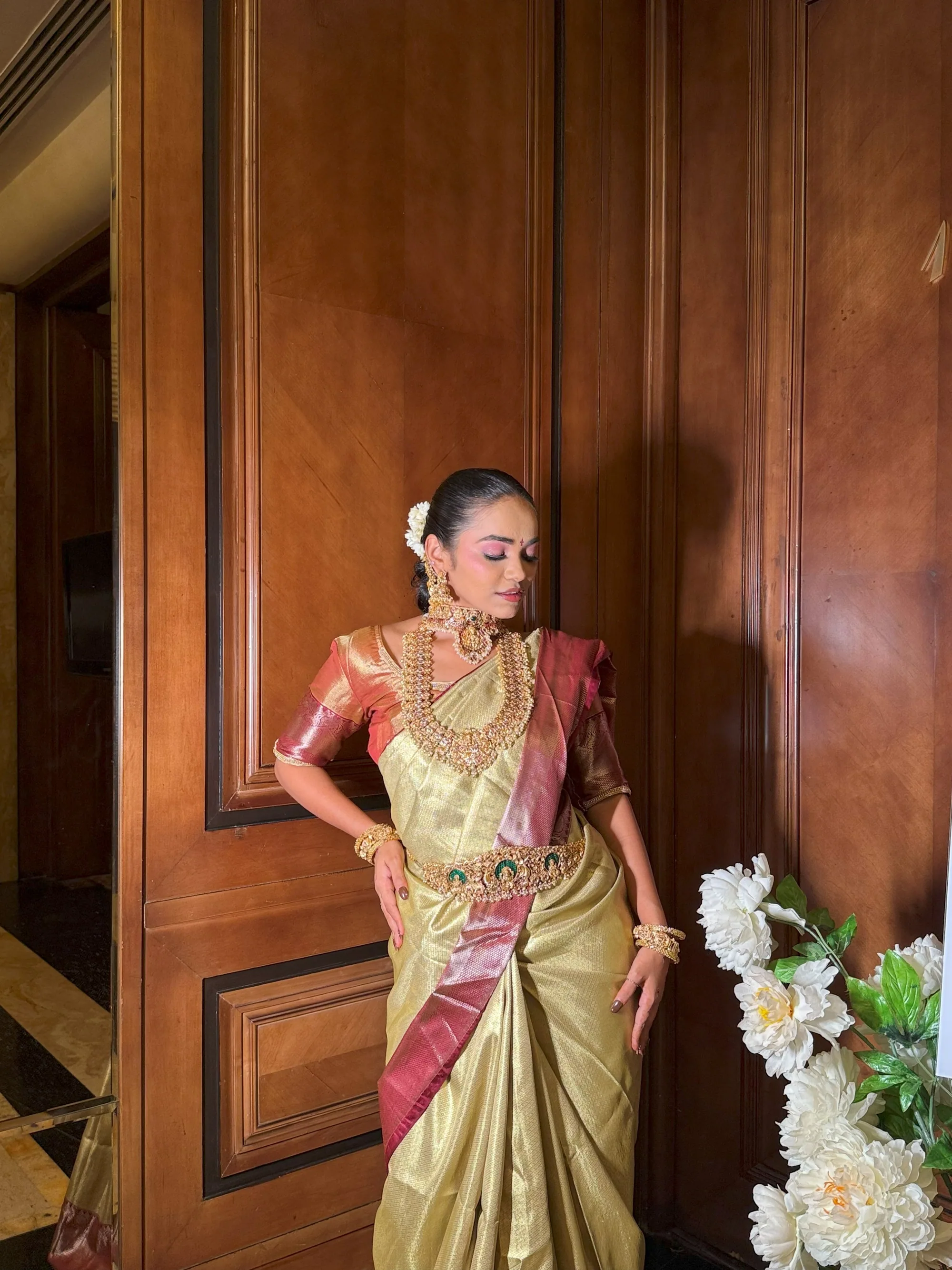 South Indian bride in gold tissue against wood panelling