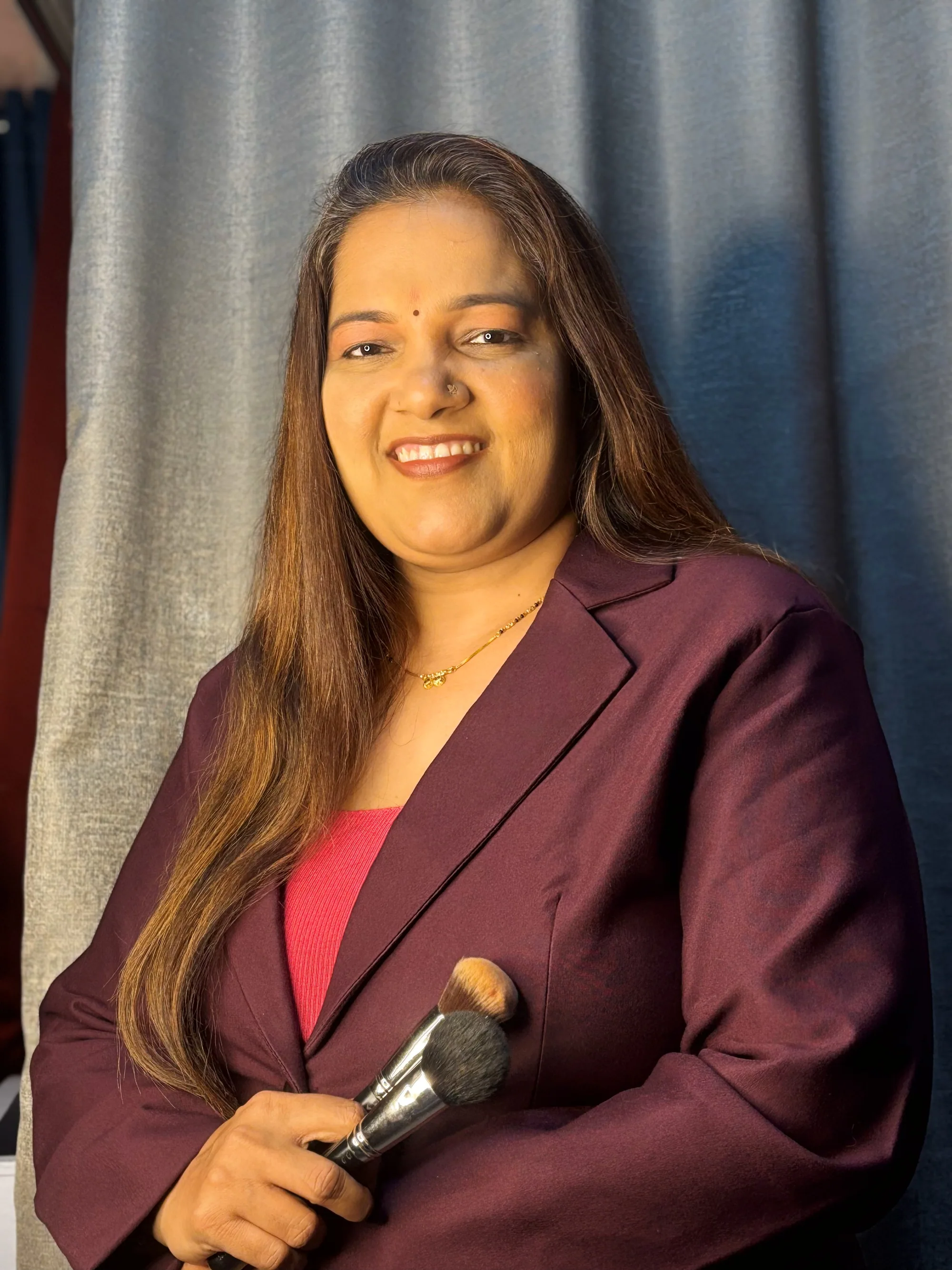 Neha Gujar, founder of Neha Makeup Academy, holding a powder brush