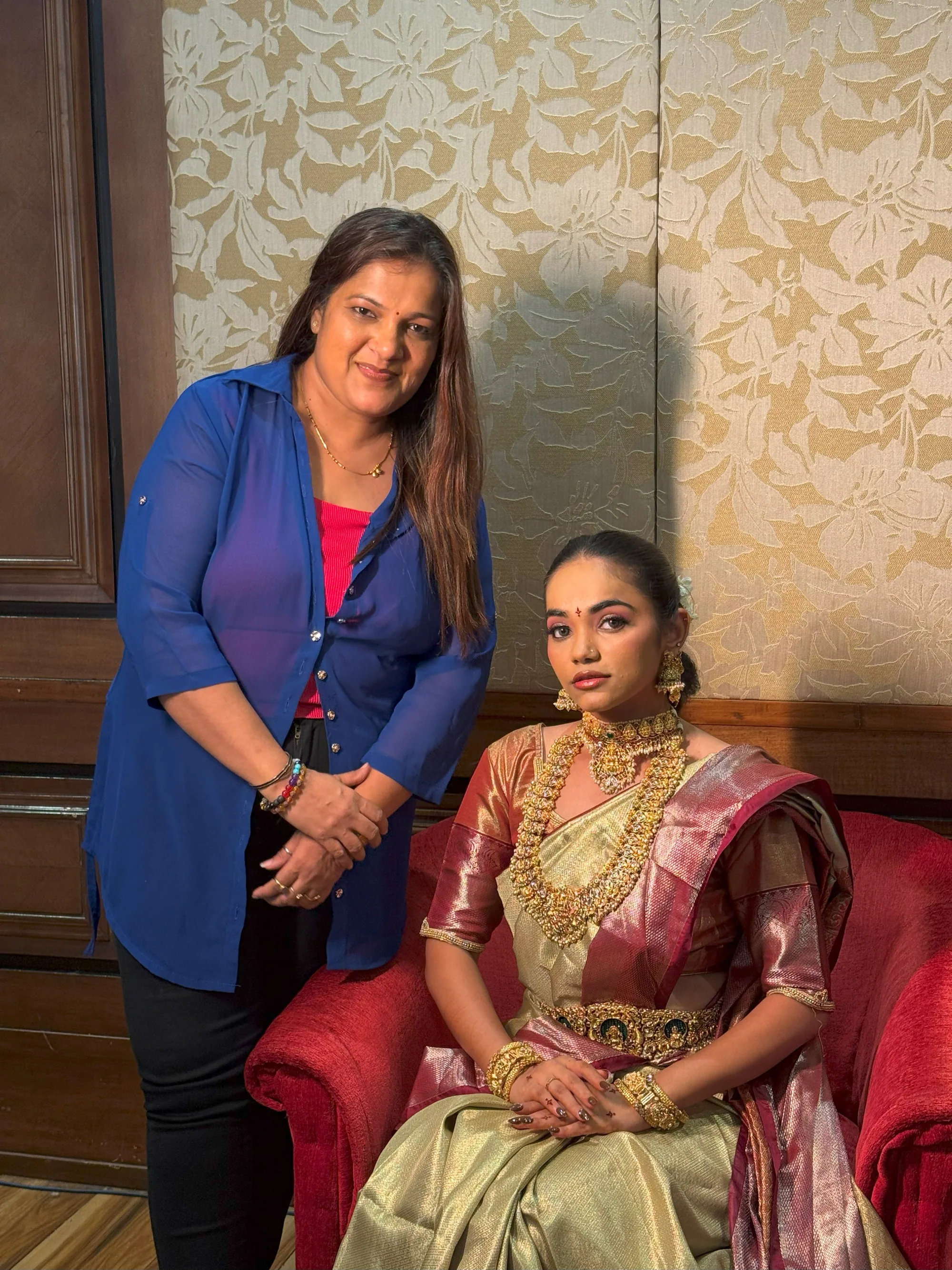 Neha beside a seated bride in a gold tissue saree
